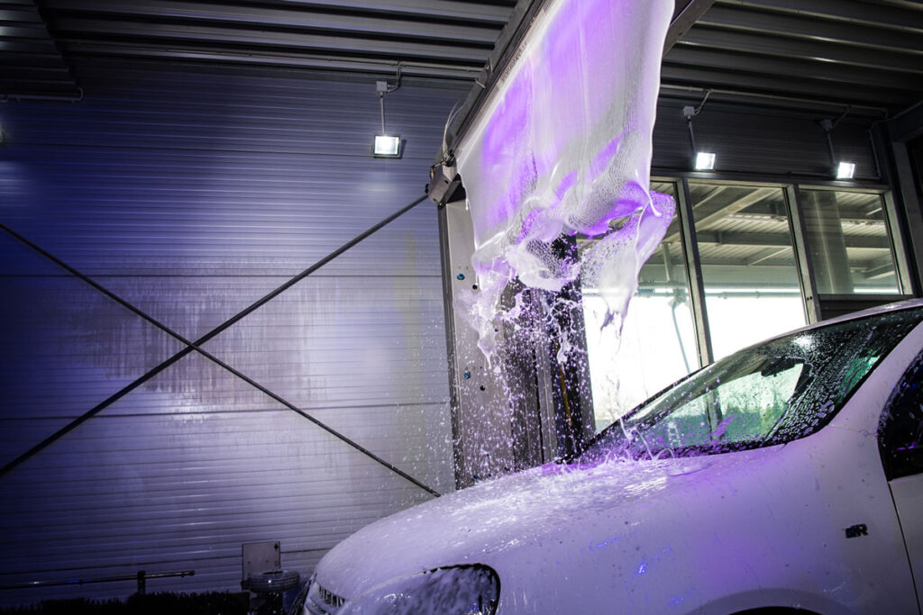Weißes Auto in Waschstraße wird gewaschen
