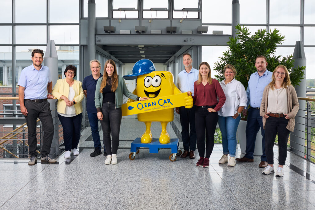 Teamfoto von CleanCar mit Maskotchen Cleany in der Mitte